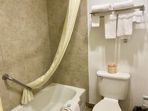 A bathroom with a bathtub, toilet, and a towel rack with folded towels. - Super 8 Downtown_2 Queen beds (Albuquerque)