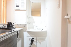 A compact kitchen with a washing machine, a sink, and a kettle. - Benten Yutaka (Minato Ward)