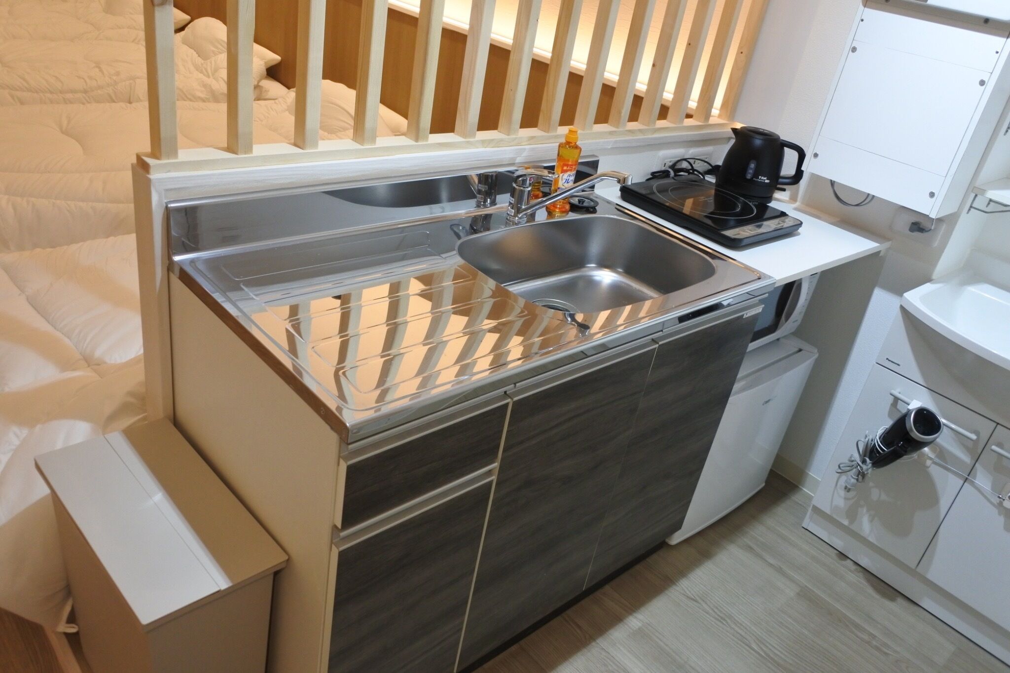 A compact kitchenette with a stainless steel sink, a coffee maker, and a small cabinet.