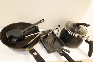 A kitchen with a frying pan, spatula, tongs, and a pot with a lid. - Benten Yutaka (Minato Ward)