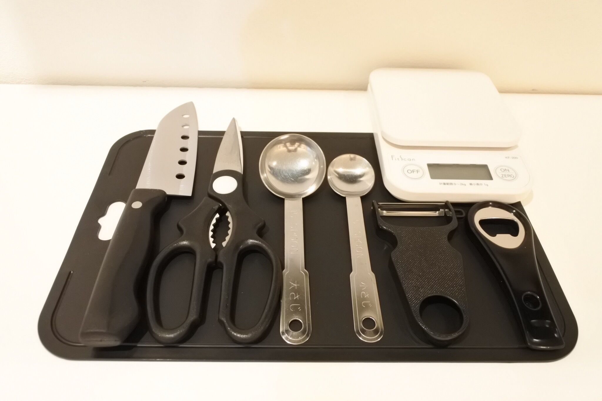 A kitchen mat with various utensils including a knife, scissors, and measuring spoons.