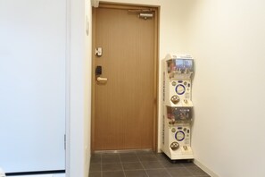 A hallway with a wooden door and a vending machine. - Benten Yutaka (Minato Ward)