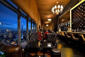 Um bar em um edifício alto, com assentos de couro, vista para a cidade e adega.