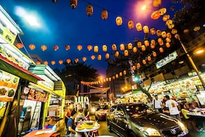 Un marché de nuit animé, avec des étals de nourriture et des lanternes.