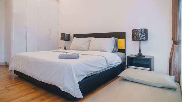 Een slaapkamer met een bed, nachtkastjes, een kledingkast en een bijzetmeubel.
