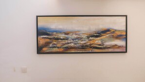 Een eetgedeelte met een tafel voor twee, een schilderij aan de muur en een moderne plafondlamp.