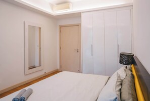 Quarto com cama, guarda-roupa, espelho e luminária no teto.