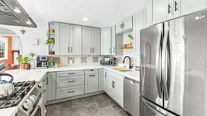 Una cucina moderna con elettrodomestici in acciaio inossidabile, mobili dai colori chiari e piastrelle a parete.