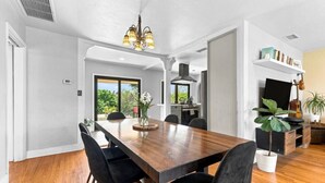 Un'area pranzo moderna con un tavolo di legno, sedie nere e un lampadario.