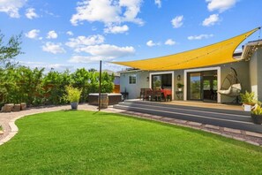 Ein modernes Haus mit überdachter Terrasse, Rasenfläche und einer Hängematte.