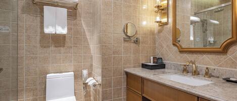 A bathroom with a toilet, sink, vanity, mirror, and towel rack.