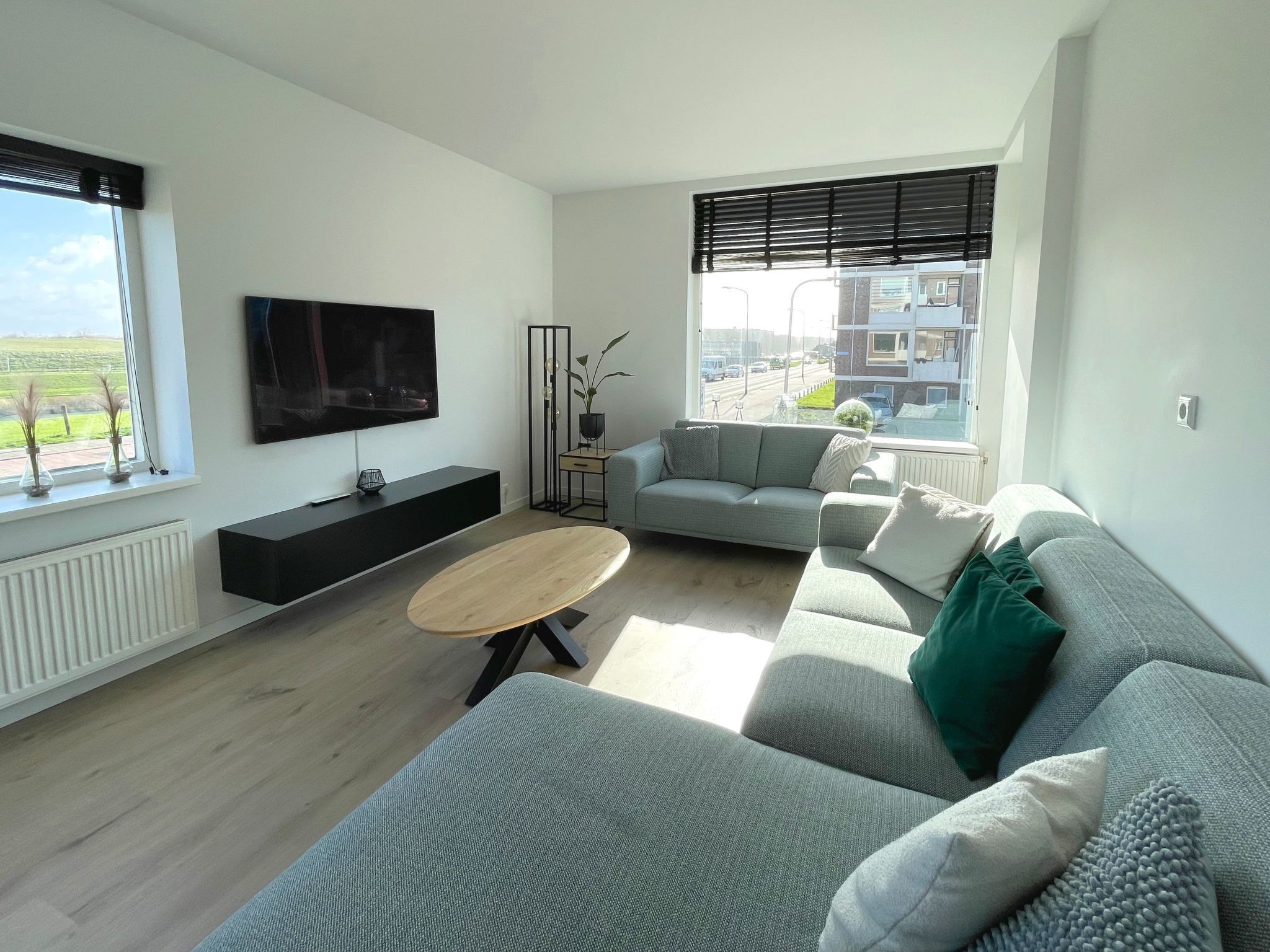 A modern living room with a grey sofa, a wooden coffee table, and a flat-screen TV mounted on the wall.
