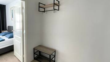 A room with a bed, a bench, and a wall-mounted shelf.