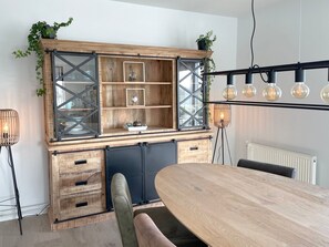 A dining area with a wooden table and chairs, a built-in bench, and a wall-mounted light fixture. - Nordseeblick by Interhome (Katwijk)