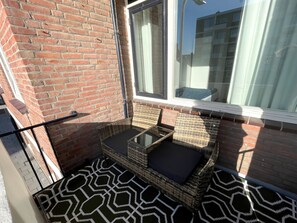 A small outdoor seating area with wicker furniture and a patterned rug. - Nordseeblick by Interhome (Katwijk)