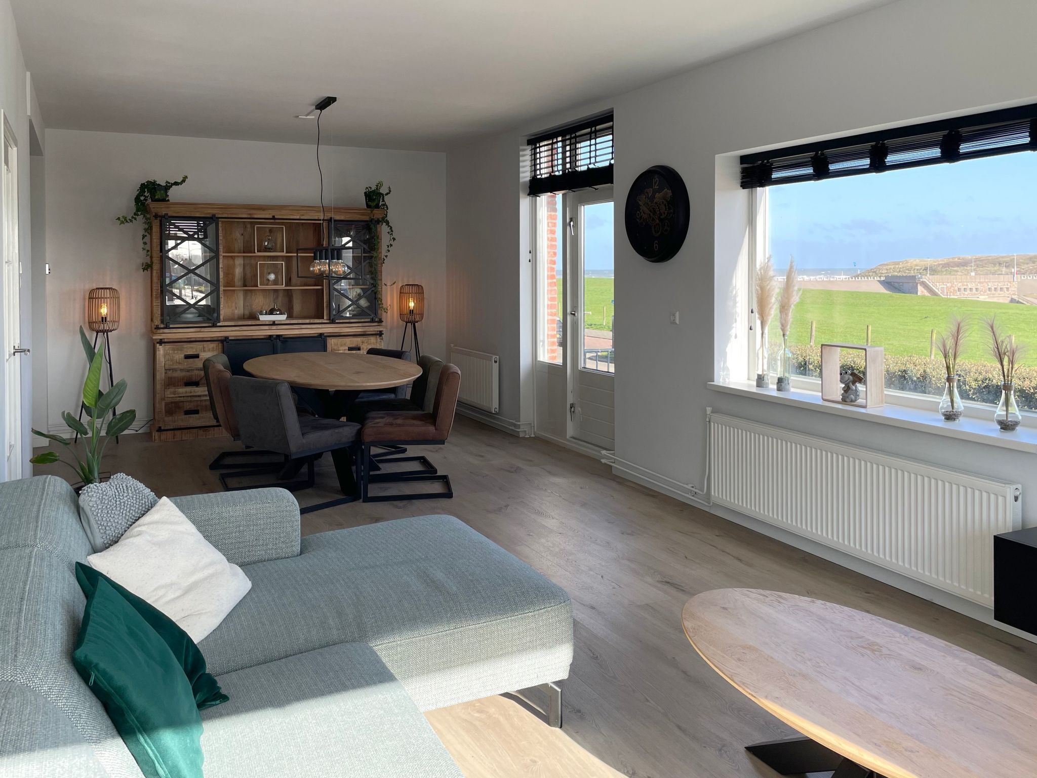 A modern living room with a sofa, a dining table, and a view of the outdoors.