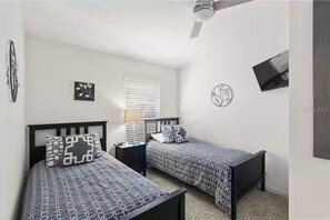 A bedroom with two beds, a ceiling fan, a window with blinds, and a wall-mounted TV. - Disney family Villa: Private Heated Pool, Golf view, Game Room with Arcade (Davenport)