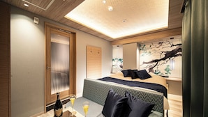 Ein Hotelzimmer mit Bett, Sitzecke, einer Champagnerflasche und Gläsern.