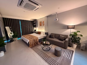 A modern bedroom with a bed, bedside table, lamp, and a large window with curtains.