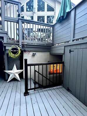 Une terrasse en bois avec une porte en métal, une décoration en forme d’étoile et une fenêtre avec des stores.