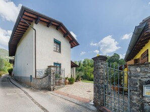 A two-story building with a stone entrance gate, a clear sky, and a paved driveway. - Casa Lulù by Interhome (Camaiore)