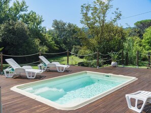 A rectangular hot tub surrounded by a wooden deck, with white lounge chairs and a rope barrier. - Casa Lulù by Interhome (Camaiore)