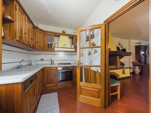A kitchen with wooden cabinets, a built-in oven, and a large window. - Casa Lulù by Interhome (Camaiore)