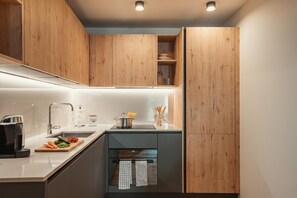 Eine moderne Küche mit Holzschränken, einer Edelstahl-Spüle und einem eingebauten Backofen.