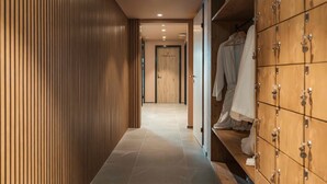 A hallway with a wooden panel wall, a tiled floor, and a clothing storage unit with hanging space. - Residenza Castanea 208 Modern Alpine Stay in San Bernardino | Ski, Hiking & Nature, San Bernardino, Switzerland (San Bernardino)