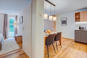 Eine moderne Küche mit Holzschränken, einem Esstisch mit Stühlen und Pendelleuchten.