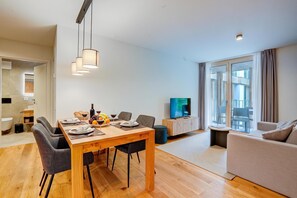 Ein modernes Wohnzimmer mit Essbereich, einem Flachbildfernseher und einem großen Fenster.