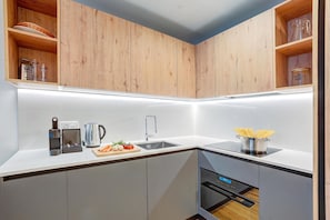 Eine moderne Küche mit Holzschränken, einer Edelstahlspüle und einem eingebauten Backofen.