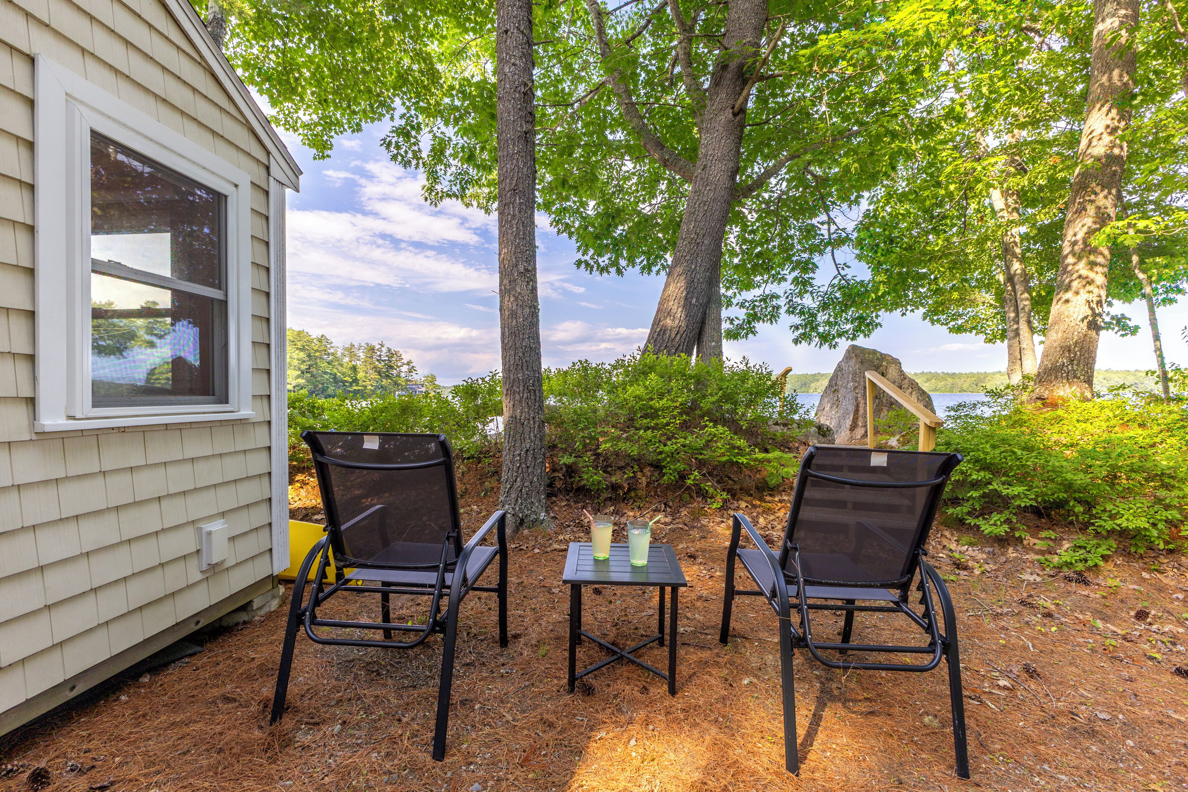 Un espace extérieur aménagé avec deux chaises et une table, une terrasse en bois et une vue sur un lac.