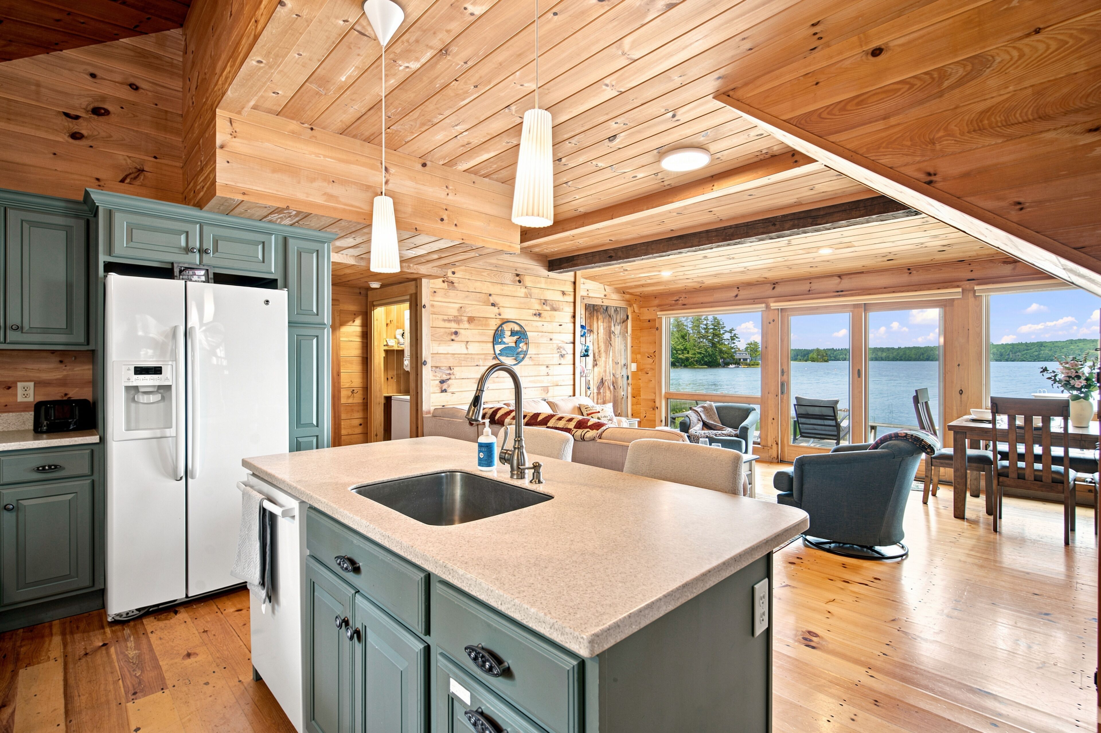 A modern kitchen with a central island, built-in cabinets, and a view of a lake through large windows.