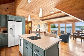 A modern kitchen with a central island, built-in cabinets, and a view of a lake through large windows.