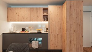 Uma cozinha moderna com armários de madeira, forno embutido e um espaço de refeições com mesa e cadeira.