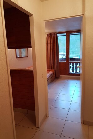 Ein Flur, der zu einem Balkon mit Meerblick führt, mit einem Bett und einem gerahmten Bild an der Wand.