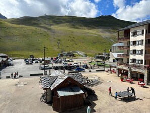 Gebirgige Landschaft mit Parkplatz, einem kleinen Holgebäude und einem Restaurant mit Außenbereich.