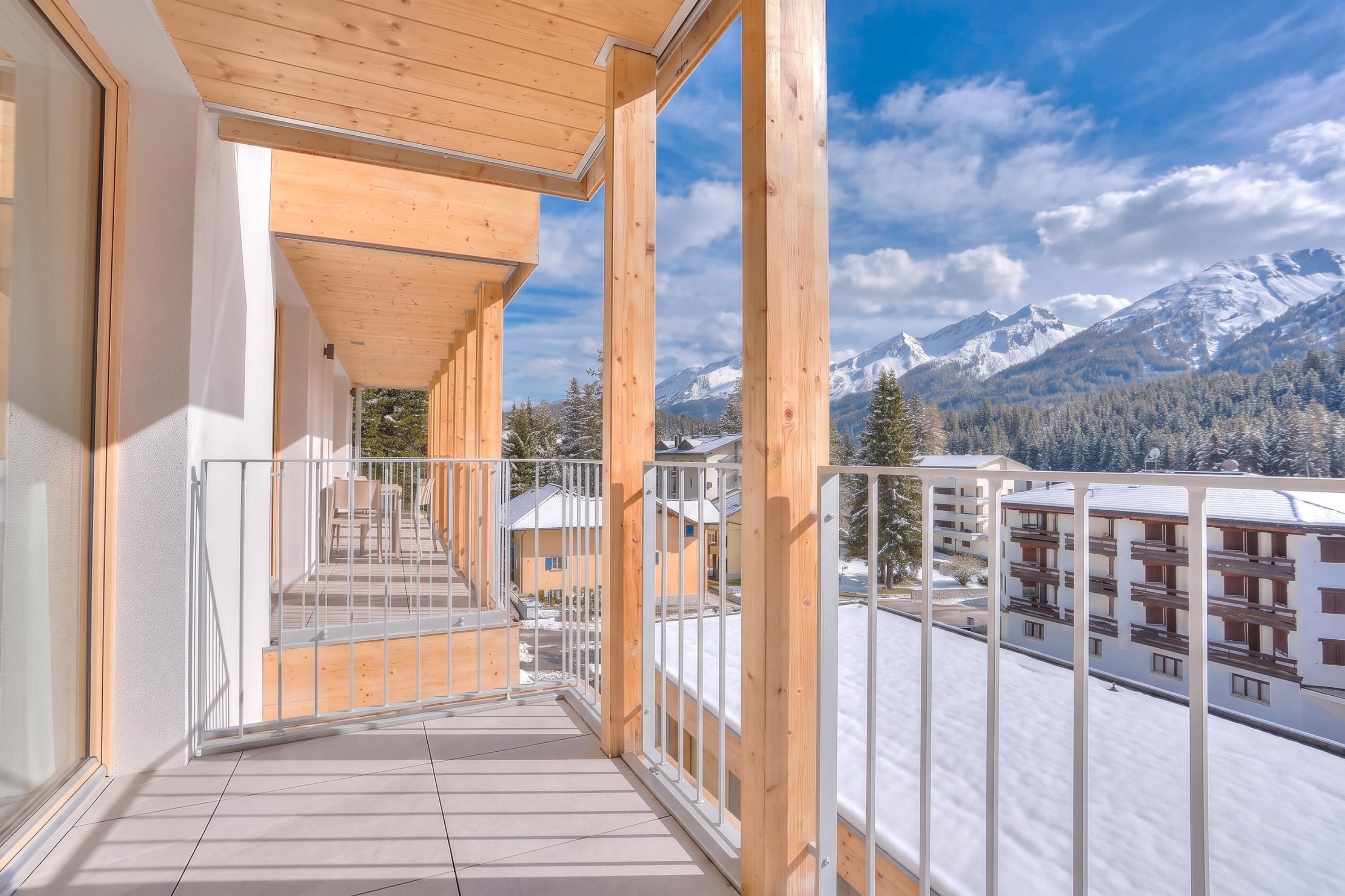 A wooden balcony with a view of snow-covered mountains.