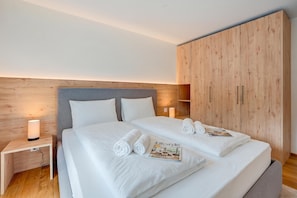 Ein Hotelzimmer mit einem Bett, einem Nachttisch, einem Holzschrank und einer Zeitschrift auf dem Bett.