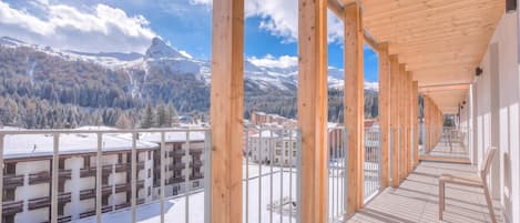 A corridor with wooden beams and a view of snow-covered mountains.