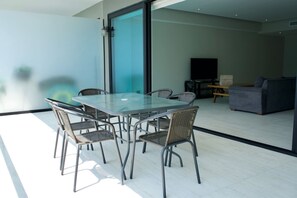 Ein modernes Wohnzimmer mit einem Glastisch, Korbstühlen, einer Couch und einem Fernseher.