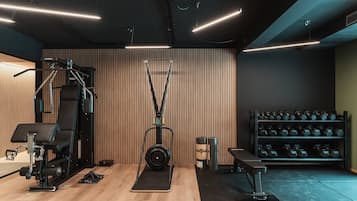 A gym with exercise equipment, a bench, and a rack of dumbbells.