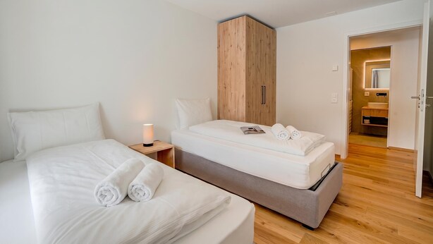 Hotelkamer met een bed, nachtkastje, kledingkast en een badkamer zichtbaar door een open deur.