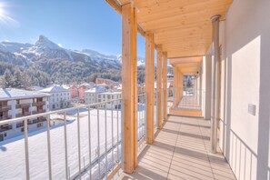Passadís amb bigues de fusta i vista a muntanyes cobertes de neu i edificis.