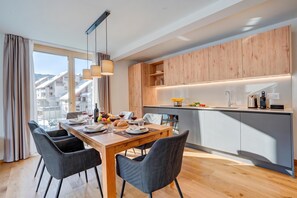 Eine moderne Küche mit Holzausstattung, ein Essbereich mit Tisch für Zwei und Blick auf die Stadt durch große Fenster.