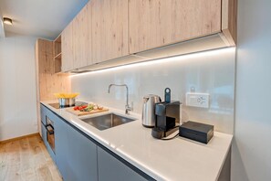 Eine moderne Küche mit Spüle aus Edelstahl, einem Wasserkocher und einer Kaffeemaschine.