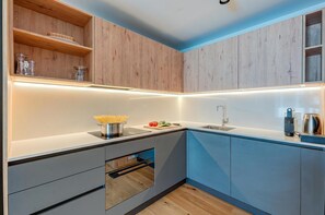Una cocina moderna con armarios de madera, horno empotrado y pileta de acero inoxidable.