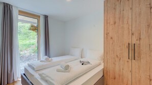 Ein Schlafzimmer mit zwei Betten, einem Holzschrank und einem Fenster mit Vorhängen.