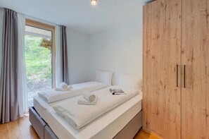 Une chambre avec deux lits, une armoire en bois et une fenêtre avec des rideaux.